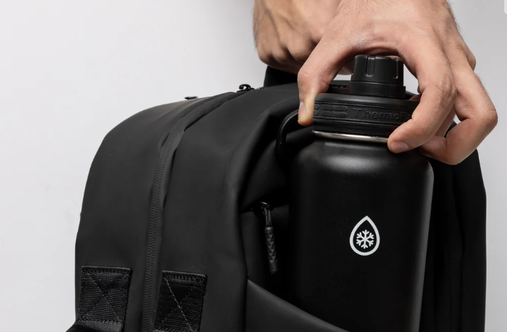 A person putting a water bottle in a bag